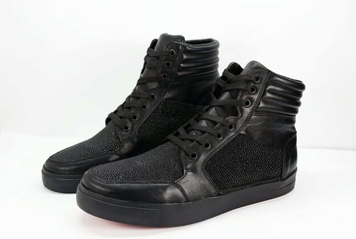 Tenis altos negros con fondo blanco e iluminación suave