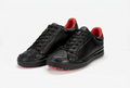 Tenis negros con detalles rojos, fondo blanco e iluminación suave