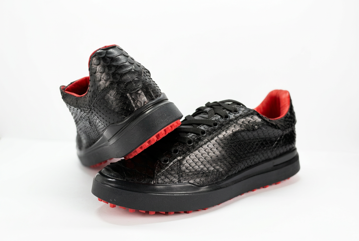 Tenis negros con detalles rojos y vista del talón sobre fondo blanco